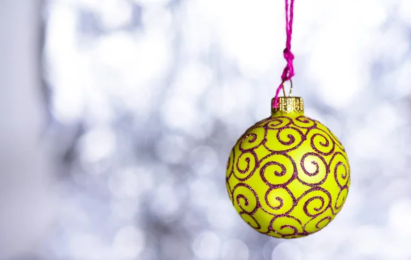 Рождественское украшение или игрушка для елки с мерцающими деталями, копировальное пространство. Праздничное украшение для елки, желтый шар с блеском декора на белом размытом фоне. Концепция орнамента — стоковое фото