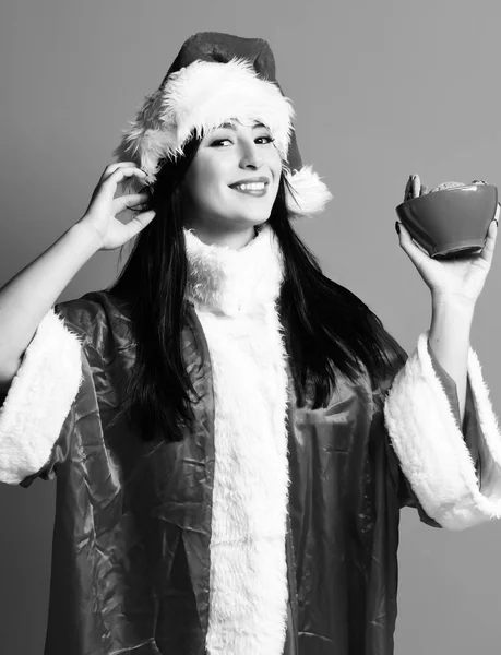 Oldukça sevimli seksi Noel Baba kız ya da yeni yıl kazak ve şapka gülümseyen esmer kadın tutan Noel veya kase kırmızı studio arka plan üzerinde xmas çikolata kalça kurabiye — Stok fotoğraf