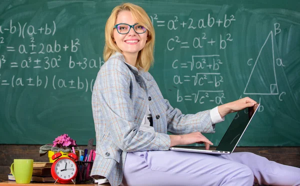 Lady lecturer know how stay in touch modern generation. Teacher of modern generation. Woman teacher hold laptop sit table classroom chalkboard background. Studying in non formal environment benefits — Stock Photo, Image