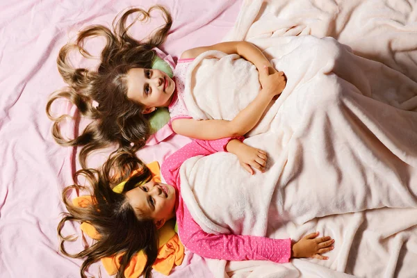 Τα παιδιά με χαρούμενα πρόσωπα και τις καρδιές στα μαλλιά στο κρεβάτι — Φωτογραφία Αρχείου