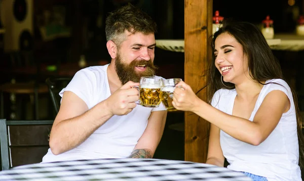 Couple in love on date drinks beer. Best friends or lover drinking in pub. Couple brutal date at pub. Man bearded hipster and girl with beer glass full of craft beer. Friendly meeting just drink beer