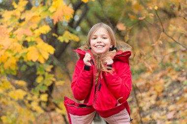 Çocuk giyim ceket sonbahar sezonu için. Giyim Sonbahar ve kavram moda. Yürüyüş çocuk sarı uzun saçlı park arka plan düşmek. Sıcak ceketle rahat hissediyorum. Kız mutlu giyim ceket kukuleta ile zevk Sonbahar Doğa
