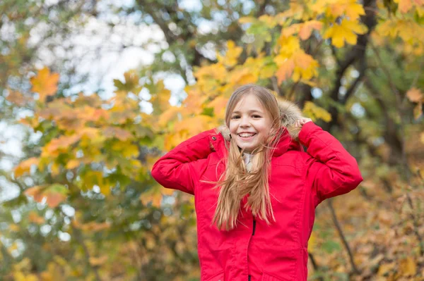 Sentiti a tuo agio con una giacca calda. Ragazza felice indossare cappotto con cappuccio godere di autunno natura. Cappotto bambino per la stagione autunnale. Autunno vestiti e concetto di moda. Bambino bionda capelli lunghi piedi caduta parco sfondo — Foto Stock