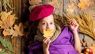 Moda trend sonbahar sezonu. Kız yatıyordu ahşap arka plan yaprakları yukarıdan düşmüş. Aksesuar moda ayrıntı ördü. Küçük çocuk kız parlak yumuşak örme şapka bere moda. Sonbahar moda aksesuar kavramı