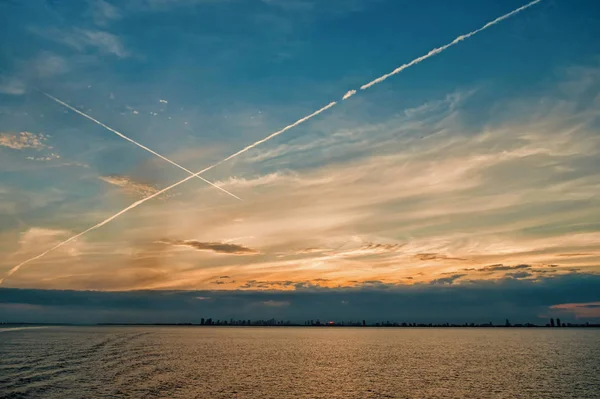 City skyline at sunset sky with plane lines, houses, water — Stock Photo, Image