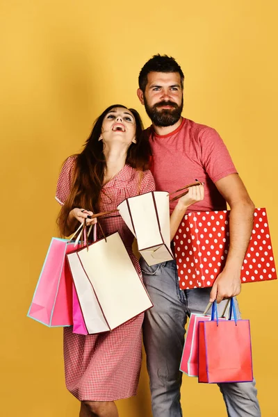 愛のカップルは黄色の背景にショッピングバッグを保持しています — ストック写真