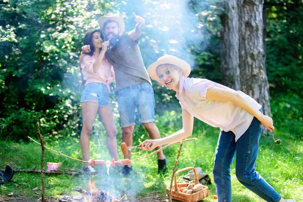 Dicas que todos os campistas devem saber sobre cozinhar fogueira. Menina de chapéu de palha cozinhar comida no fundo natureza fogueira. Alimentos para cozinhar em pau. Dicas fáceis para melhorar a sua cozinha fogueira. Dicas de acampamento — Fotografia de Stock