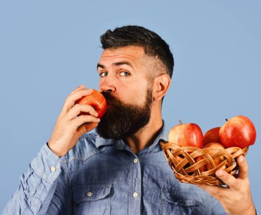 Adam hasat yiyor. Sakin yüzlü çiftçi kırmızı elmayı öpüyor.