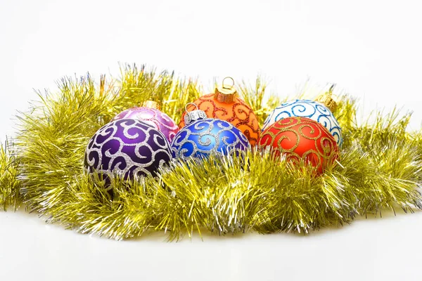 Christmas ornaments balls lay on golden tinsel as eggs in nest. Balls for decoration on shimmering tinsel, white background. Beginnings concept. Balls as eggs in nest symbol of beginning