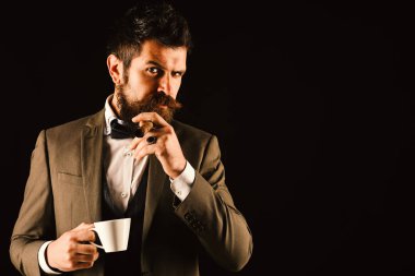 Patron sakallı, bir fincan kahveyle puro içiyor.