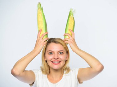 Kız neşeli oynak ruh tavşan kulakları olgun Mısır tutun. Gıda vejetaryen ve sağlıklı organik ürün. Hasat ve eğlenceli. Vejetaryen beslenme kavramı. Kadın beyaz zemin üzerine sarı Mısır Mısır koçanı tutun