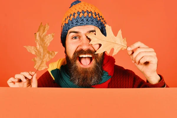 Guy with excited face wears warm hat on orange background