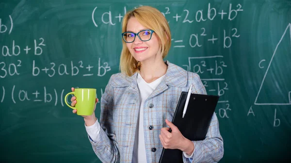 Es hora de relajarse. Encuentra tiempo para relajarte y mantenerte positivo. El maestro bebe té o café y se mantiene positivo. Mantenga una actitud positiva hacia el trabajo. Mujer con taza de té y carpeta de documentos pizarra de fondo — Foto de Stock