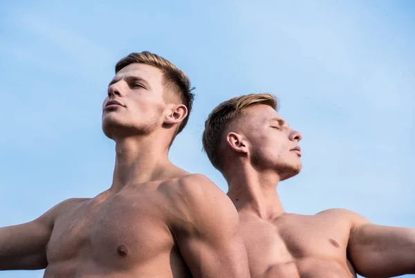 Men muscular chest naked torso sky background. Men muscular athlete bodybuilder relaxing lean each other. Masculinity and sexuality. Sexy torso attractive body strong macho. Attractive twins relaxing
