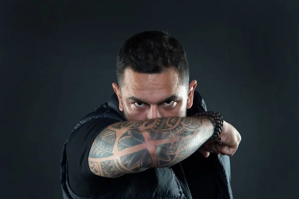 Do tattoos hide lack of masculinity. Man brutal guy cover face with tattooed arm. Tattooed elbow hide male face dark background. Visual culture concept. Tattoo can function as sign of commitment — Stock Photo, Image