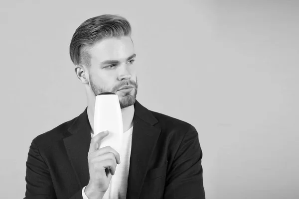 Kerl mit Borsten hält Flaschenshampoo, kopiert Platz. Männer genießen Frische nach dem Haarewaschen mit Shampoo. Haarpflege und Beauty Supplies Konzept. Mann nachdenklich Gesicht halten Shampoo-Flasche, grauer Hintergrund — Stockfoto