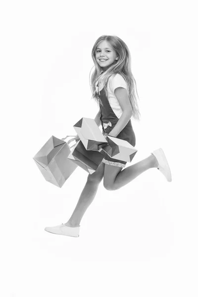 Chica en la cara sonriente lleva racimos de bolsas de la compra, aislado sobre fondo blanco. Niña con el pelo largo aficionado a las compras. Concepto de compras. Chica le gusta comprar ropa de moda en el centro comercial —  Fotos de Stock