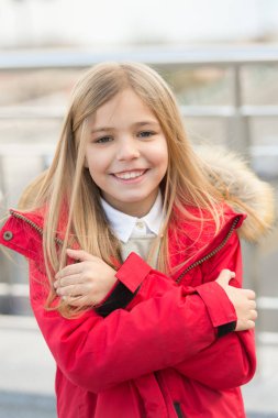 Çocuk gülümseyen kız kaputa kürklü Mont ceket giymek ama soğuk geliyor. Soğuk hava kavramı. O buz gibi. Bebek kendini soğuk hava nedeniyle sarılmak. Çocuk açık ısınmak deneyin. Kış soğuk sezon sonbahar