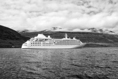 Zevk için seyir. Cruise gemi denizde dağ manzarası Sejdisfjordur, İzlanda üzerinde. Okyanus gemisi denizde dağlar bulutlu gökyüzü üzerinde. Yaz tatil ve gezi. Macera ve keşif