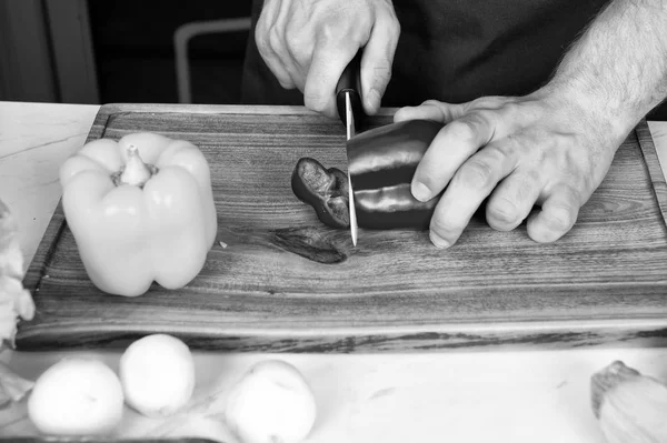 Рука скибочку перець з керамічних ножів. Овочі отримати вирізати на дерев'яні обробна дошка. Приготування їжі та кулінарні рецепти. Вегетаріанське меню та здорового харчування. Концепція органічних продуктів — стокове фото