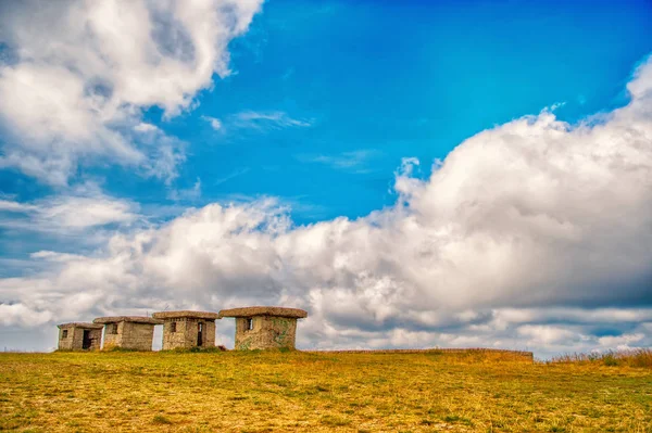 Kleine steenachtige lege huizen op het groene gras en bewolkte hemel — Stockfoto