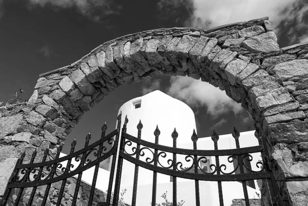 Iron gate and stone arch in Mykonos, Greece. Archway structure or architecture. Whitewashed building on sunny outdoor. Summer vacation on mediterranean island. Wanderlust and travel concept — Stock Photo, Image