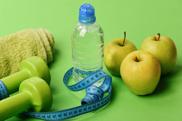 Dumbbells in bright green color, water bottle, measure tape, towel