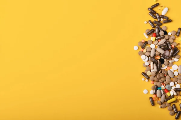 Conjunto de coloridas píldoras dispersas sobre fondo amarillo — Foto de Stock