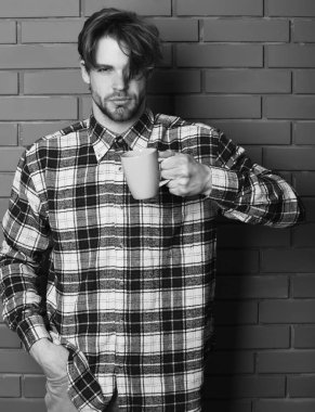 Duvarda fincanı tutan yakışıklı adam.