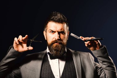Uzun sakallı adam tıraş bıçağı ve makas tutuyor..