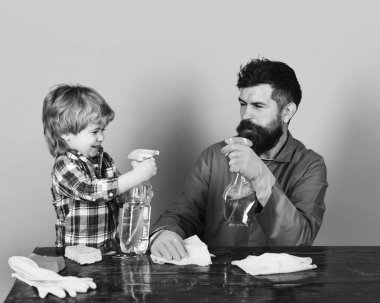 Baba ve oğul mavi arka planda temizlik malzemeleriyle oynuyorlar..