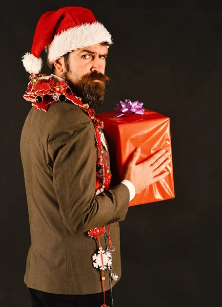 Concetto di decorazioni di Capodanno. Manager con barba tiene regalo rosso . — Foto Stock