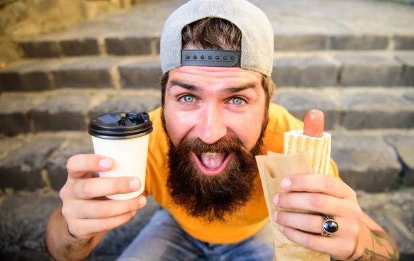 Hipster come cachorro quente. Hipster desfrutar de copo de papel de bebida de cachorro quente. Homem barbudo desfrutar de almoço rápido escadas fundo. Refeição de fast food para almoço. A energia proveniente dos alimentos de rua contribui significativamente para a dieta — Fotografia de Stock