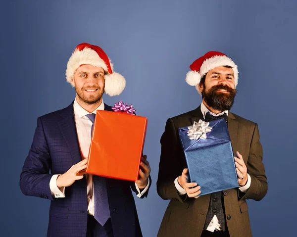 Mężczyźni w eleganckich garniturach i kapeluszach Santa na niebieskim tle. — Zdjęcie stockowe