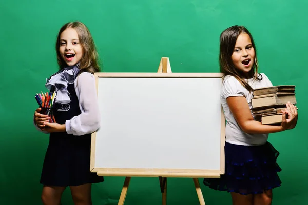 Schoolgirls next to whiteboard on green background — Stock Photo, Image