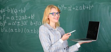 Dijital teknolojileri kavramı. Eğitimci zeki kadın modern dizüstü sörf internet kara tahta arka plan ile. Kadın öğretmen giyim gözlük laptop internet'te sörf tutar. Temel okul eğitimi