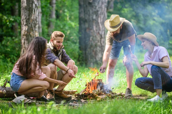 Malvaviscos tostados popular actividad grupal alrededor de la hoguera. Amigos de la compañía preparan malvaviscos asados merienda fondo de la naturaleza. Empresa juventud camping bosque asando malvaviscos. Actividad de camping — Foto de Stock