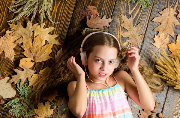Autumn melody concept. Child listen music relaxing top view. Autumn music playlist. Best songs about fall. Enjoy music and relax. Happy childhood. Kid girl wooden background listen music headphones