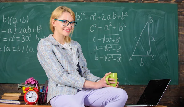 Prenditi una pausa per rilassarti. Donna insegnante sorridente tiene tazza bere sedersi tavolo in classe lavagna sfondo. Condizioni di lavoro degli insegnanti. Condizioni di lavoro che i futuri insegnanti devono considerare — Foto Stock