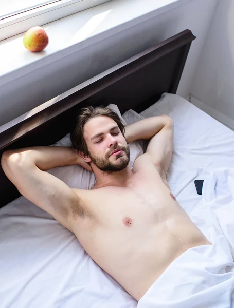 Хлопець сексуальний мачо поклав білий одяг. Чоловік спить сонним бородатим обличчям, відпочиваючи. Приємна концепція розслаблення. Нехай твоє тіло почуватиметься комфортно. Чоловік незахищений красивий хлопець голий торс розслабляючий ліжко — стокове фото