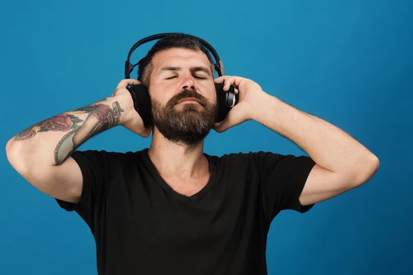 El hombre sostiene los auriculares sobre fondo azul. Placer, música y estilo de vida — Foto de Stock