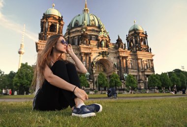 Berlin Katedrali 'nin önünde güneş kremi sürerek oturuyor.