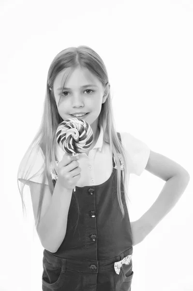 Söta utseende. Liten flicka äter godis på pinne isolerade på vitt. Barnet ler med lollipop. Lycklig unge med swirl karamell. Mat och efterrätt. Diet och bantning — Stockfoto