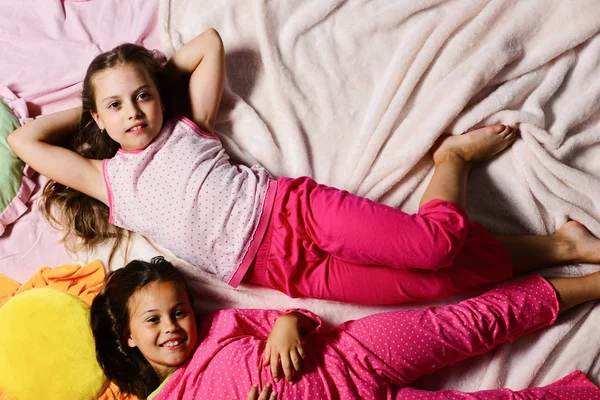 Crianças com rostos sorridentes têm descanso na cama — Fotografia de Stock