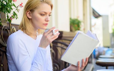 Mükemmel sabah kavramı. Kupa kahve ve ilginç kitap en iyi kombinasyonu mükemmel hafta sonu. Kadın açık havada içki kafe teras vardır. Kız içki kahve popüler yazar tarafından okuma yeni bestseller kitap ise