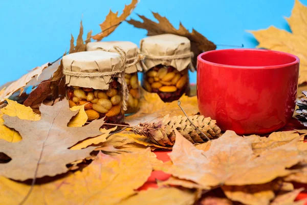 Set three honey natural sweets in jars and mug of tea background covered fallen leaves. Natural homemade treats autumn season keep healthy. Autumnal beverage with homemade natural sweets