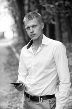 Sonbahar Park cep telefonu olan bir adam. İşadamı ile smartphone açık. Blog ve sosyal ağ web günlüğü. Modern yaşam ve iş iletişimi için yeni teknoloji