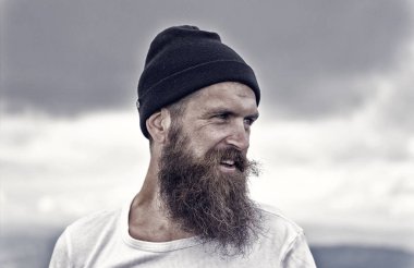 bulutlu gökyüzü üzerinde şapkalı gülümseyen yakışıklı sakallı