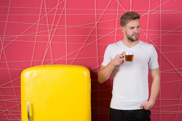 Утренний чай, чтобы начать свой день. Мужчина вдохновил улыбку утренним напитком возле холодильника. Холостяк держит чашку чая или кофе на ретро-холодильнике на розовом фоне. Утренний чай идеи и рецепты