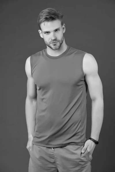 Deportista seguro. Hombre ropa deportiva guapo fondo violeta. Atleta deportista confiado pone las manos en los bolsillos. Concepto de masculinidad y confianza. Deportista con banda de fitness reloj inteligente —  Fotos de Stock